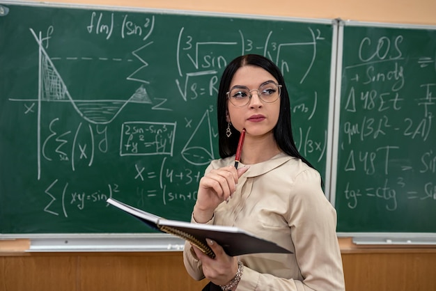 teacher explain completing mathematical equations on chalkboard in classroom. studying concept