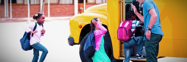 Teacher giving high five to kids while entering in bus