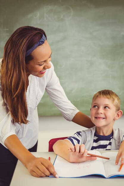 Teacher helping a boy with his homework in classroom