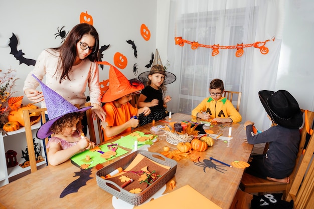 Teacher helping creative children to make paper bookmarks