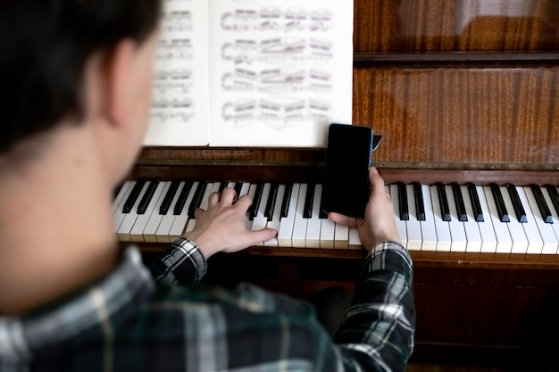 Teacher holding his phone during his online piano lesson