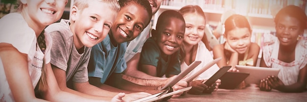 Teacher and kids lying on floor using digital tablet in library