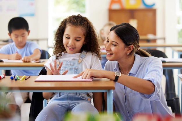 Teacher learning and helping girl in classroom for knowledge studying and assessment Preschool smile development and happy kid or student with woman for education with notebook in kindergarten