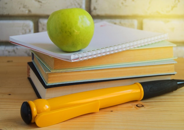 Teacher's Day concept and back to school green Apple large souvenir pen on books and notebooks