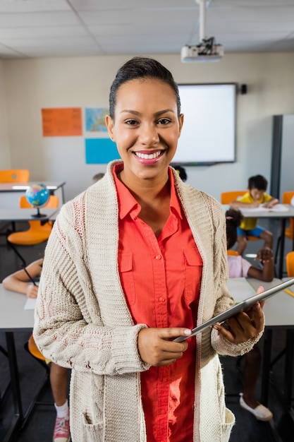 A teacher standing with tablet pc in classroom