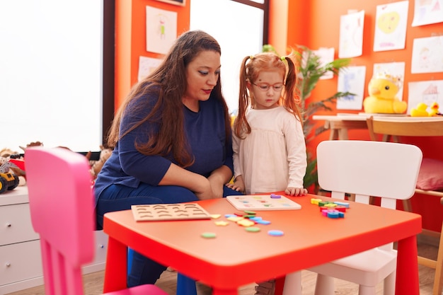 Teacher and student playing with maths puzzle game at kindergarten