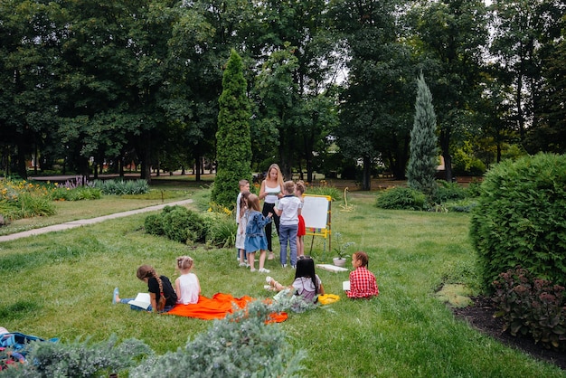 A teacher teaches a class of children in an outdoor Park. Back to school, learning during the pandemic.