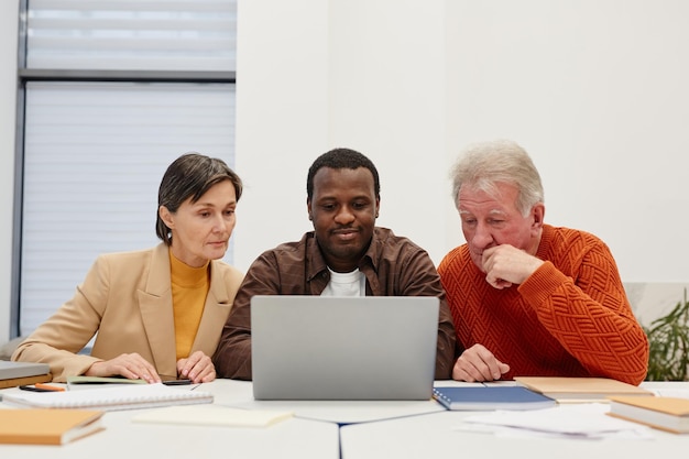 Teacher teaching his students to use laptop