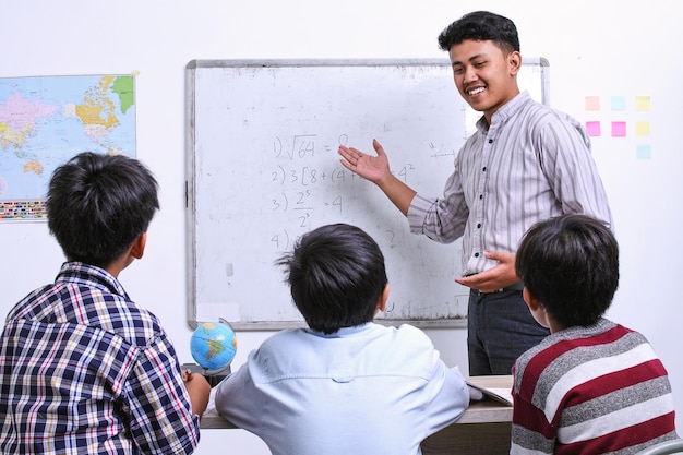 Teacher teaching math on whiteboard to elementary children in classroom