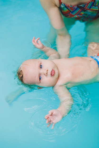 Teaching children to swim A baby learns to swim in a pool with a trainer Baby learning to swim Child development