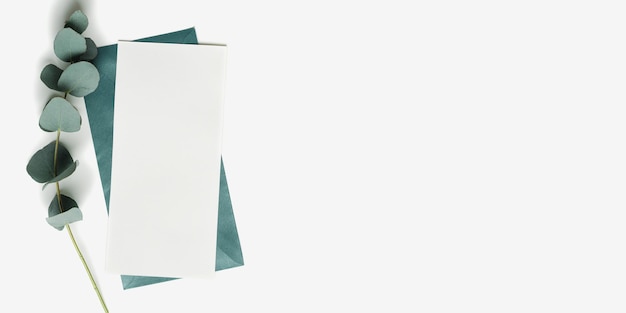 Teal color envelope and blank paper card mock up and branches eucalyptus leaves on