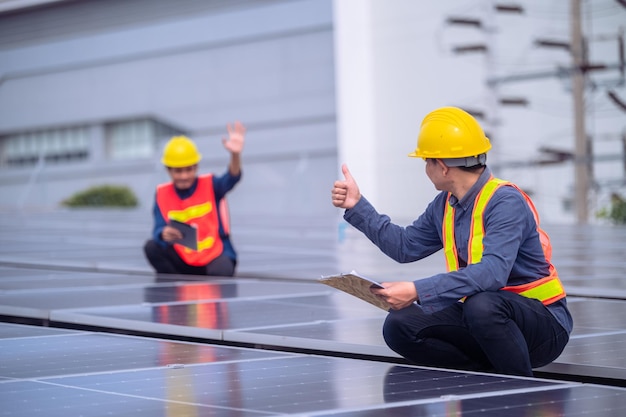 Team Asian Engineer inspecting quality of solar power solar cell energy system on rooftop of factory