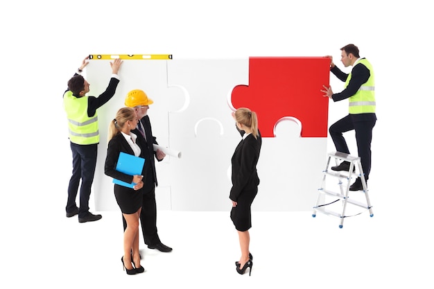 Team of business man and workers making business assmebling puzzle together isolated on white background