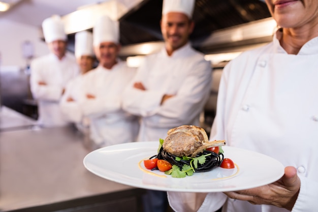 Team of chefs with one presenting a dish 