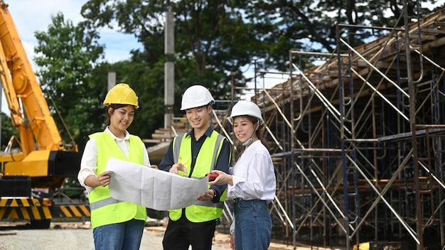 Team of civil engineer and specialists inspect commercial industrial building construction site with crane in the background