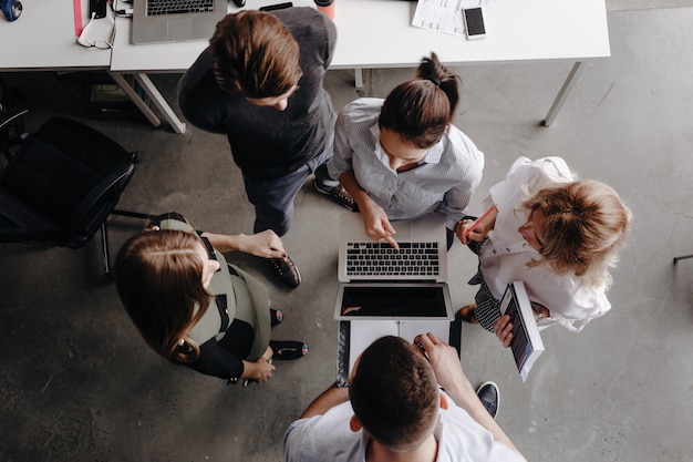 Team of colleagues works with laptop and discuss the project in a stylish modern office. Work process in the office.