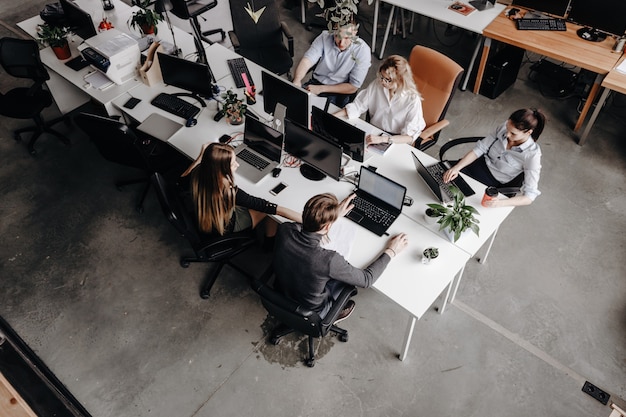 Team of colleagues works with laptop and documents sitting at the desks in a modern office. Work process in the office.