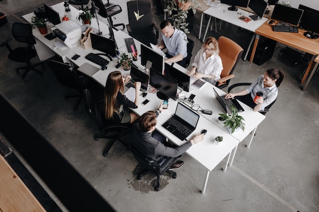 Team of colleagues works with laptop and documents sitting at the desks in a modern office. Work process in the office.