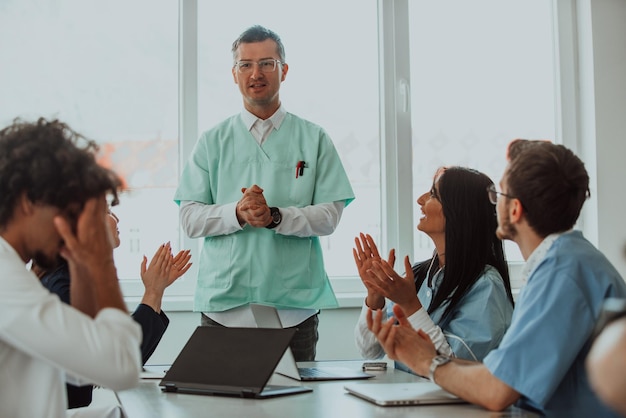 A team of doctors and a medical nurse applauding their colleague after a presentation in a meeting r