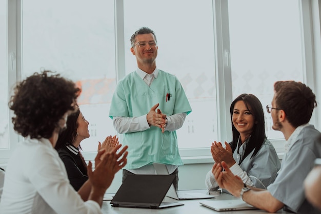 a team of doctors and a medical nurse applauding their colleague after a presentation in a meeting r