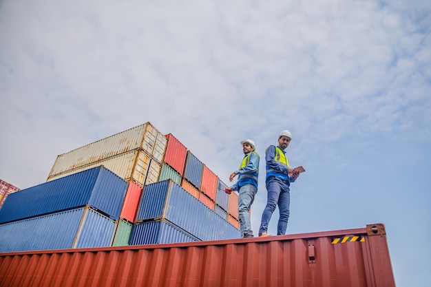 Team Engineers are inspecting the transportation of cargo with containers inside the warehouse Container in export and import business and logistics