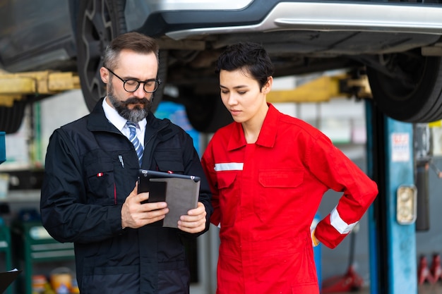 Team of mechanics discussing at the repair garage. Professional Expertise mechanic team working in automobile repair garage.