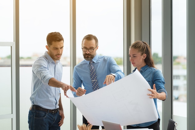 Photo team of multiethnic architects working on construction plans in meeting room. engineers discussing on project in office.