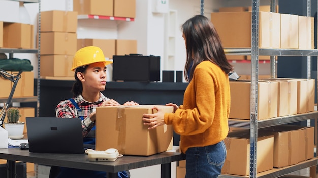 Team of people doing quality control in warehouse, checking stock production before sending retail order packages. Young employees doing teamwork in storage room for management. Handheld shot.