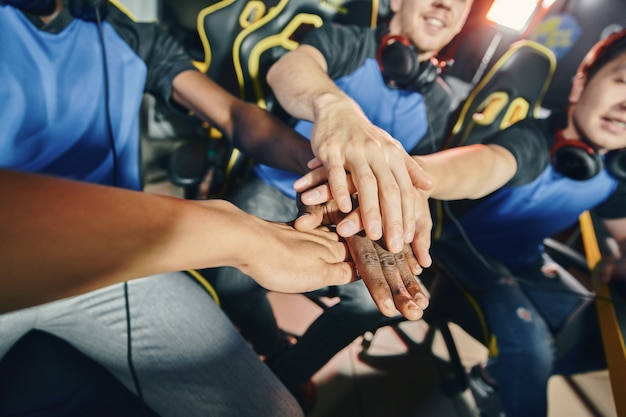 Team of professional cyber sport gamers putting hands together before starting esports tournament