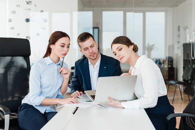 Team of professionals looking at laptop and discussing business in the office