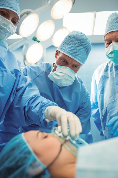 Team of surgeons adjusting oxygen mask on patient mouth in operation theater