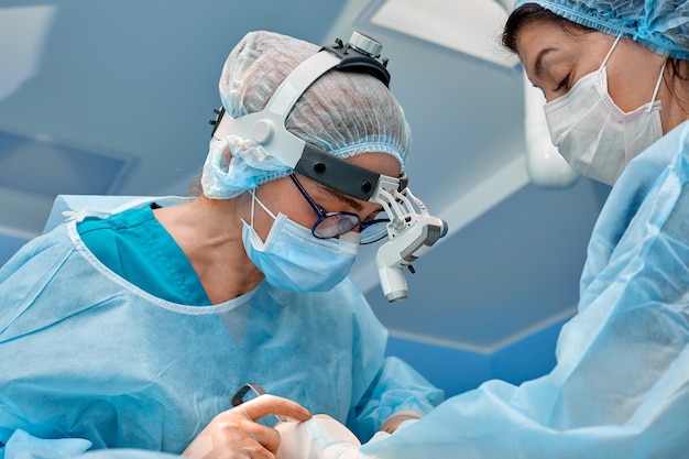 Team of surgeons makes an invasive operation. Portrait of surgeons close-up. Work with a coagulating instrument, vascular coagulation