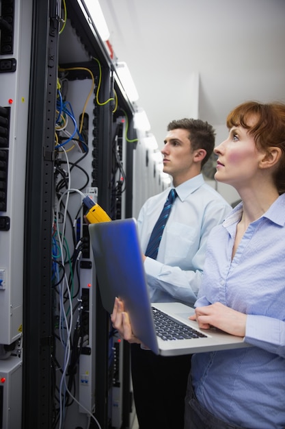 Team of technicians using digital cable analyser on servers in large data center