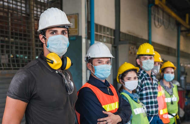 Team workers wearing facial mask and protective helmet