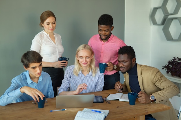 team of young beautiful people in the office at the table with a laptop