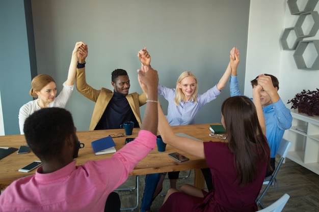 team of young beautiful people in the office with their hands up