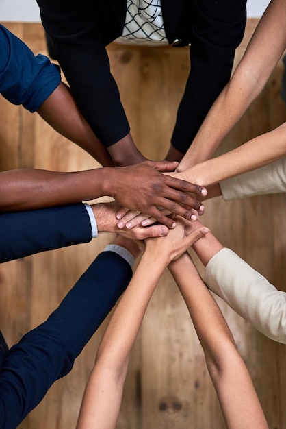 Teamwork brings out our best High angle shot of a group of unidentifiable businesspeople piling their hands in unity in the office