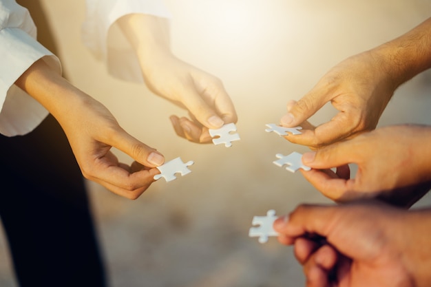 Photo teamwork concept with people completing jigsaw puzzle.