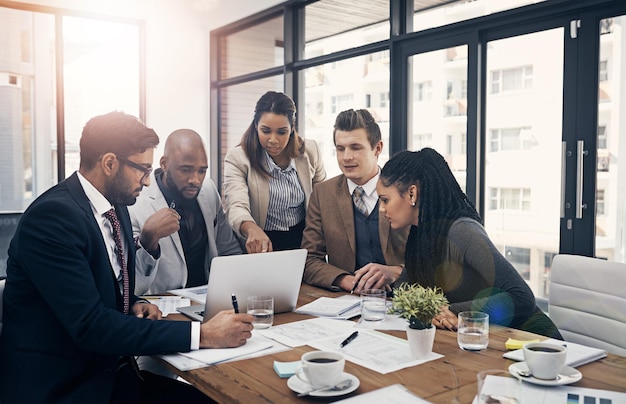 Teamwork is the ultimate productivity booster Shot of a group of young businesspeople using a laptop together during a meeting in a modern office