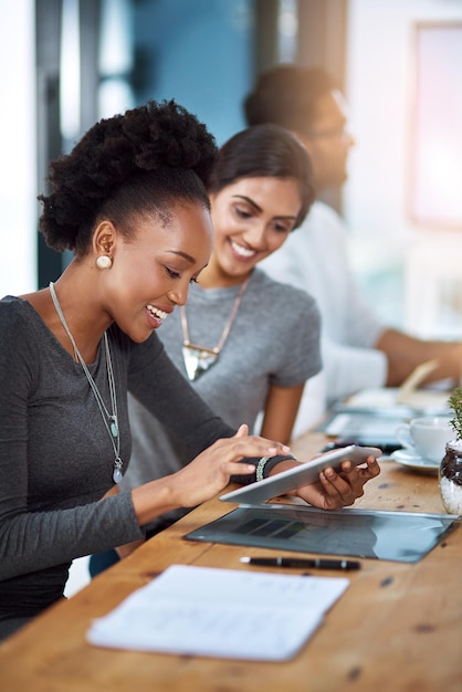 Teamwork and productivity go hand in hand Shot of two young colleagues using a digital tablet together at work