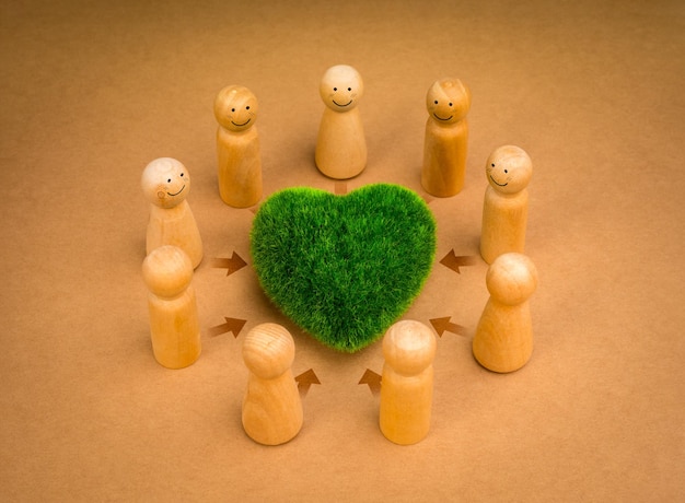 Teamwork revitalizing volunteer group cooperation community eco sustainability environment responsibility concepts Green heart surrounded with wooden people figures on recycle paper background