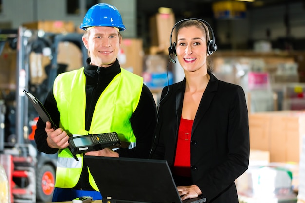 Teamwork, warehouseman or forklift driver and female supervisor with laptop, headset and cell phone, at warehouse of freight forwarding company  a forklift 