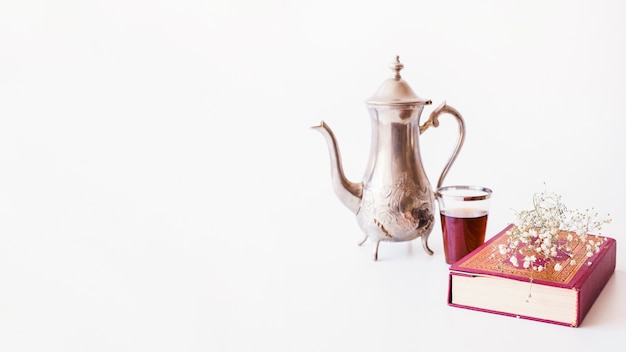 Teapot and book on white 