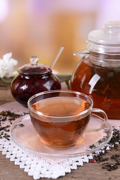 Teapot and cup of tea on table on light background