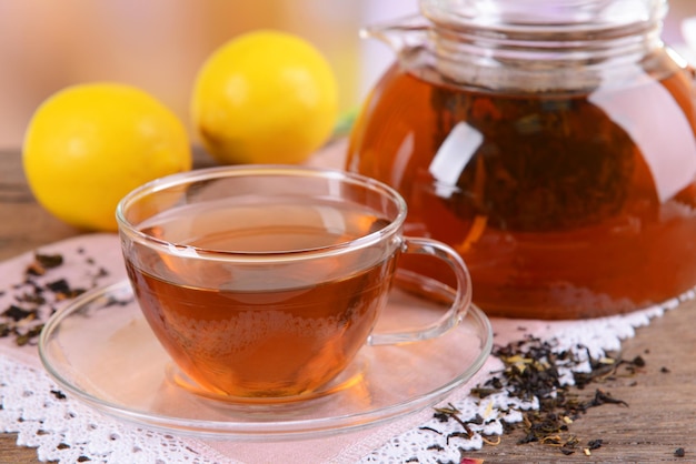 Teapot and cup of tea on table on light background