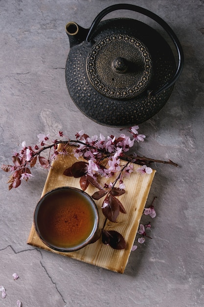 Photo teapot and cup of tea with blossom branch