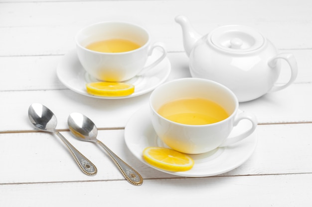 Photo teapot and cups of tea on a white wooden background