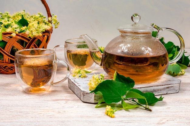 Teapot and two cups of tea with a linden tree on a wooden table Healing tea