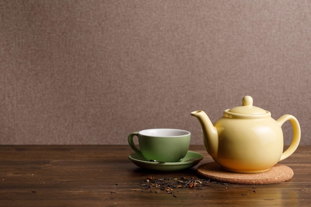 Teapot with cup on wooden background Copy space