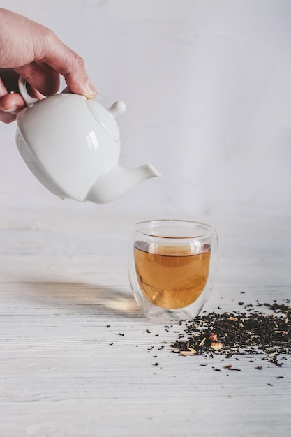 Teapot with a glass of tea dry tea leaves